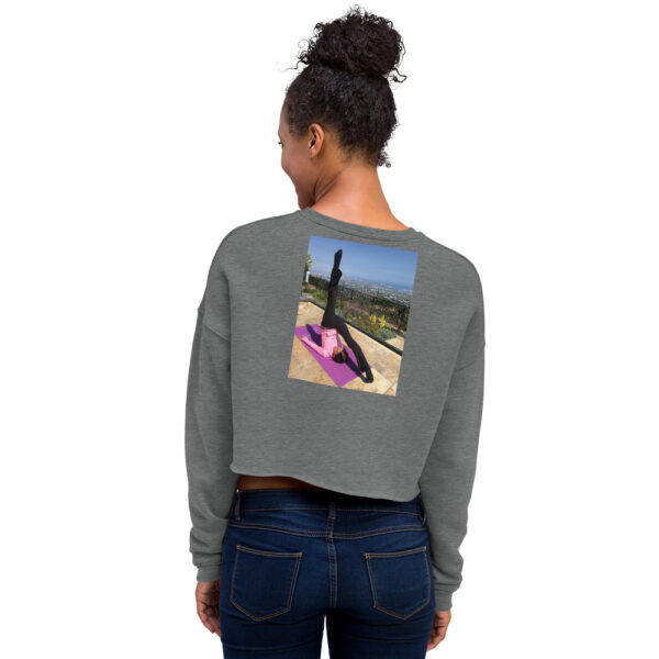 Back of woman modelling a gray colored cropped sweatshirt with a graphic of a woman in a pilates pose.