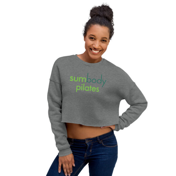 Woman modelling gray cropped sweatshirt with Sumbody Pilates logo across chest.