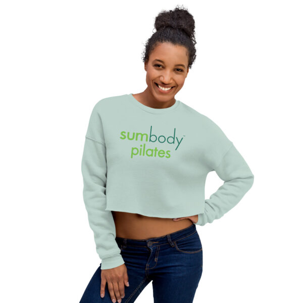 Woman modelling seafoam colored sweatshirt with Sumbody Pilates logo across chest.