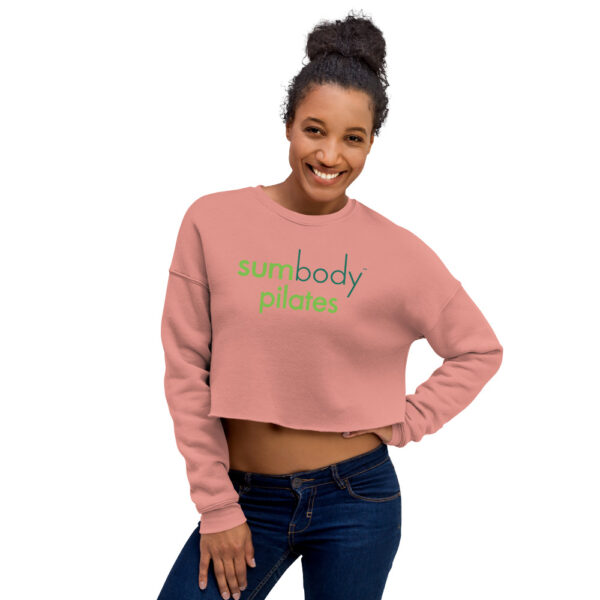 Woman modelling muted pink cropped sweatshirt with Sumbody Pilates logo across chest.